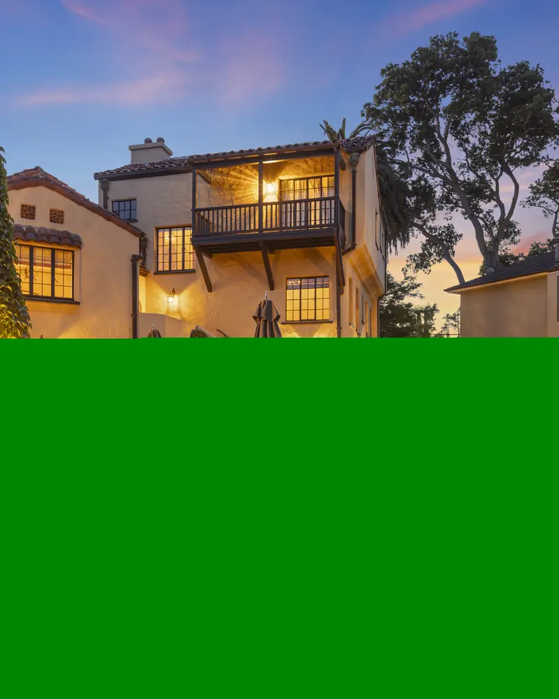 Twilight view of an illuminated Mediterranean-style residence and landscaped courtyard